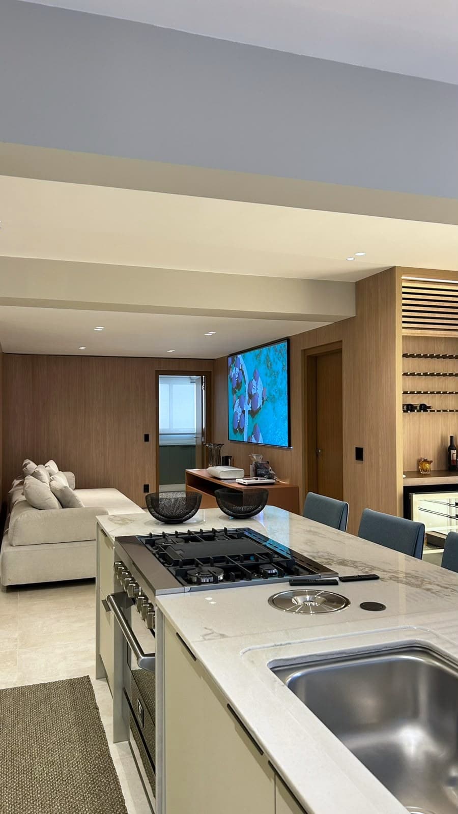 Cozinha com ilha em mármore aberta para o living e a adega ao fundo