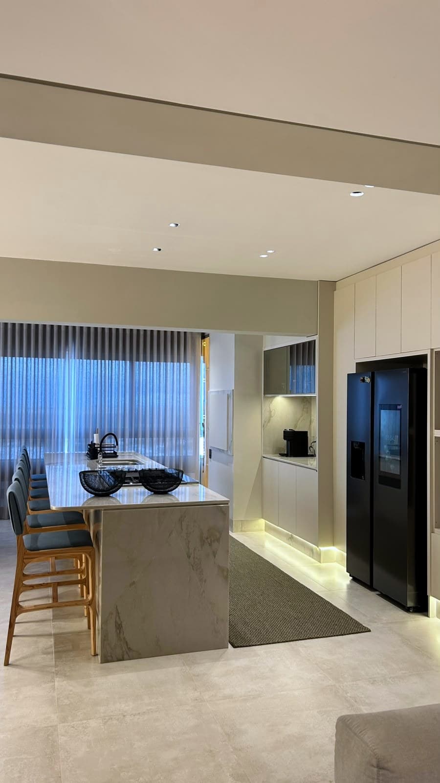 Cozinha integrada com geladeira side by side e iluminação em cove